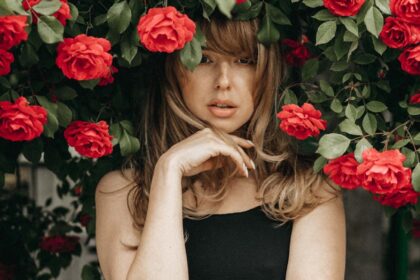 blonde woman standing under rose bush