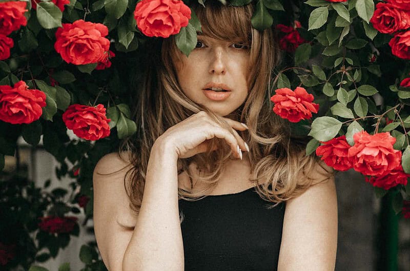 blonde woman standing under rose bush
