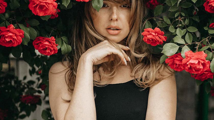 blonde woman standing under rose bush