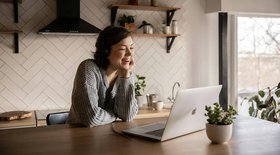 smiling woman talking via laptop in kitchen