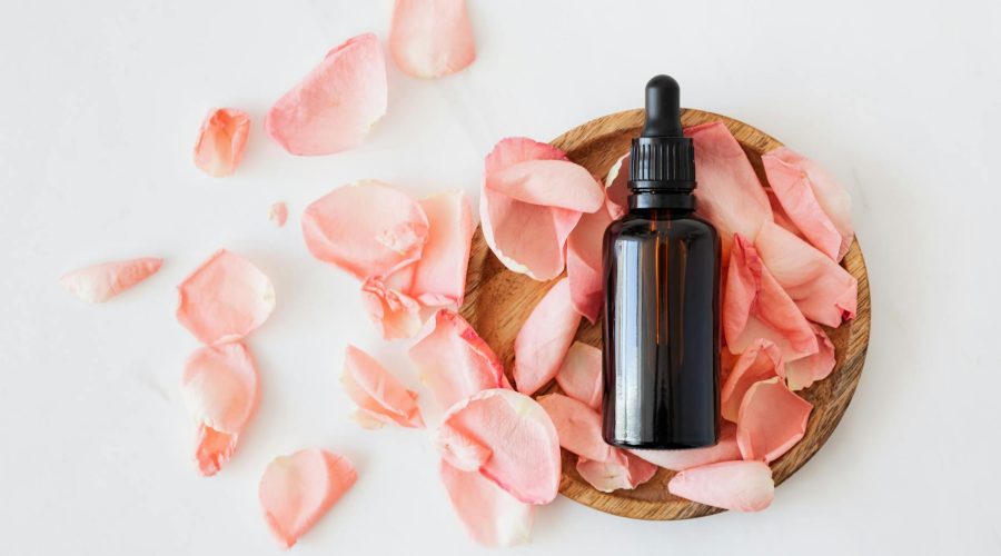 composition of cosmetic bottle with pink rose petals and wooden plate